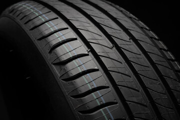 New car tire. Road wheel on dark background. Summer Tire with asymmetric tread design. Driving car concept.