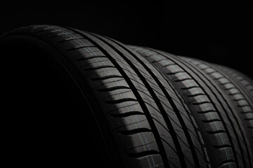 New car tires. Group of road wheels on dark background. Summer Tires with asymmetric tread design. Driving car concept.