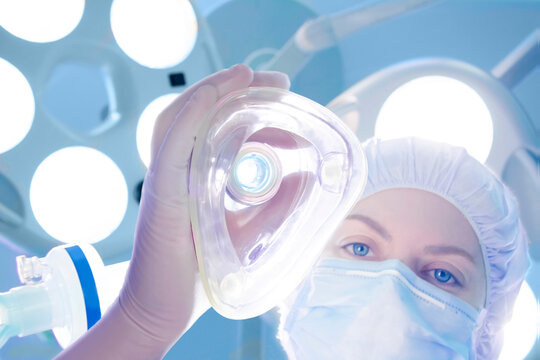 Anesthesiologist holding oxygen mask for induction in operating room