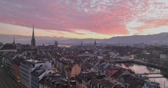 Wide Establishing Aerial Sunset or Sunrise Shot of Zurich City Center Landmark with Twilight Red Sky. Amazing Drone Footage of Switzerland Cityscape Riverside Aerial panorama at night.