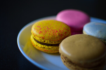 Sweet fresh macaroons in a white plate on the black background