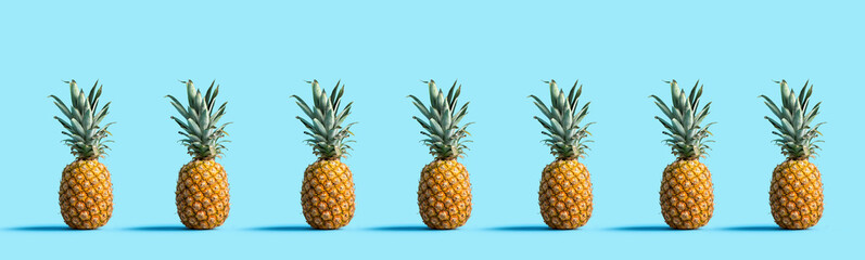 Many pineapples on a solid color background