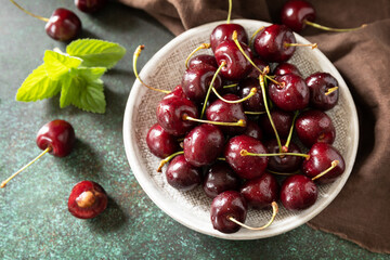 Fresh ripe organic berry red sweet cherries on plate on a stone tabletop.