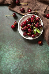 Fresh ripe organic berry red sweet cherries on plate on a stone tabletop. Food from above. Copy space.