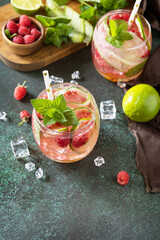 Soft drinks, healthy beverage, slimming water. Refreshing detox drinks made from organic raspberries, cucumbers, lime and mint leaves on a stone table. Copy space.