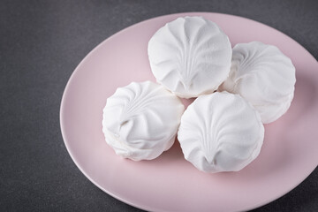 White marshmallows on a pink plate on a grey table