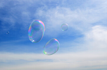 dreams, inspiration, fantasies concept - light airy transparent soap bubbles fly in the blue cloudy...
