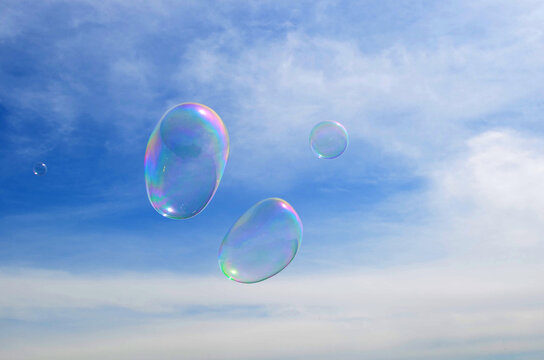 dreams, inspiration, fantasies concept - light airy transparent soap bubbles fly in the blue cloudy sky.