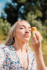 A young woman holds a duckling in her hands and closes her eyes enjoying 