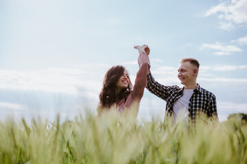 Young couple, a guy and a girl walk around the field and laugh
