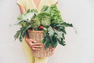 Young woman carrying basket with fresh vegetables.