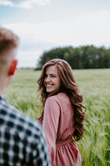 Young couple, a guy and a girl walk around the field and laugh