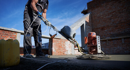 Side view of worker in special uniform working with equipments on construction. Concept of process preparing work for building walls in good summer weather.