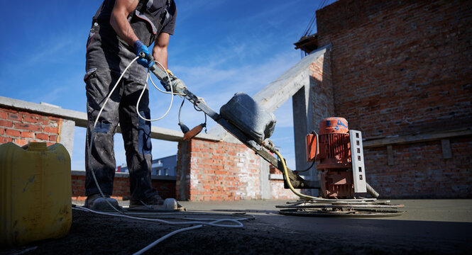 Side view of worker in special uniform working with equipments on construction. Concept of process preparing work for building walls in good summer weather.