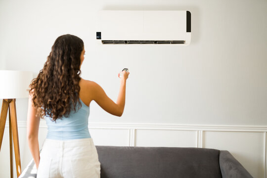 Rear view of a woman using the air conditioner at home