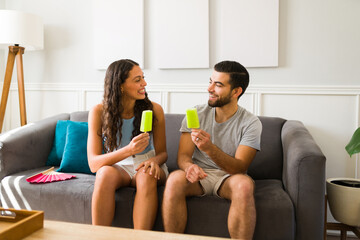 Excited couple eating popsicles at home in the summer