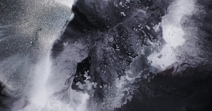 Black, white ink abstract background. Close-up, liquid paint dynamic mixed. Motion of frosty white ice on black water texture. Fluid art 4k footage. Black silver, monochrome abyss abstract background