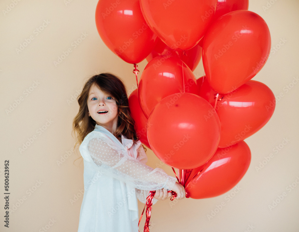 Wall mural Cute little girl with heart shaped balloons on Valentine's day. family, love. gifts for the holiday.