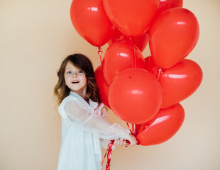Fototapeta na wymiar Cute little girl with heart shaped balloons on Valentine's day. family, love. gifts for the holiday.