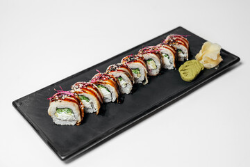 Sushi, rolls. Chinese and Asian cuisine, sets of rolls of ginger and soy sauce lie on a black board with chopsticks. Sushi is made in sets