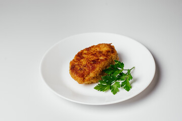 Fried cutlet on a plate. A hearty dish of minced meat decorated with greens