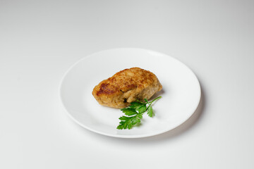 Fried cutlet on a plate. A hearty dish of minced meat decorated with greens