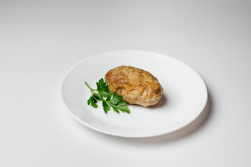 Fried cutlet on a plate. A hearty dish of minced meat decorated with greens