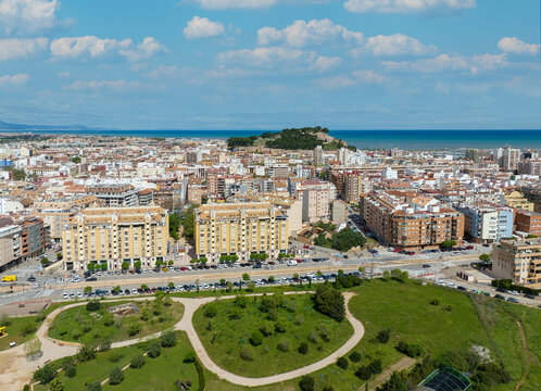 Denia on the Costa Blanca. A drone shot in sunshine. The castle can be seen in the center of the city. In the foreground is a park for relaxing.