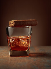 Whiskey with ice and cigar on a rusty background.