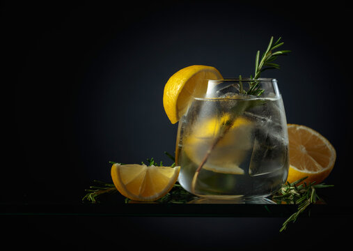 Cocktail gin tonic with ice, lemon, and rosemary.