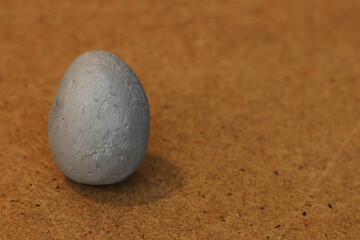 Fototapeta na wymiar Gray artificial egg on a wooden background.