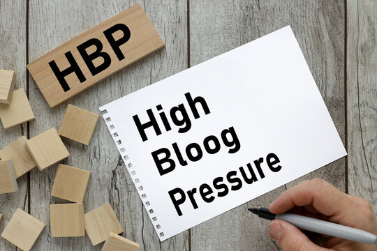 HBP High Blood Pressure text on notepad page and wood block on wooden table