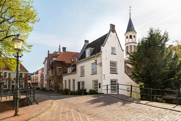 Narrow street in Amersfoort with old historic canal houses and in the background the tower of the Elleboogkerk.