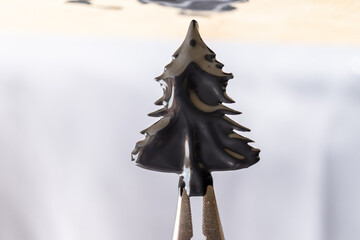 pinza sosteniendo figura de pino cubierta de pintura negra fresca espesa irregular con fondo claro - obrazy, fototapety, plakaty