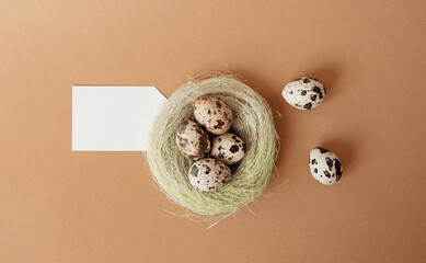 Quail eggs in a sisal nest on a pastel beige background. Easter decoration, egg minimalist design, modern design template. Happy Easter greeting card, top view.