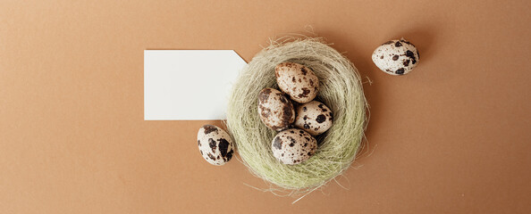 Quail eggs in a sisal nest on a pastel beige background. Easter decoration, egg minimalist design, modern design template. Happy Easter greeting card, top view.