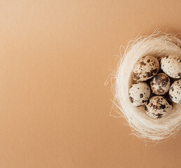 Quail eggs in a sisal nest on a pastel beige background. Easter decoration, egg minimalist design,...