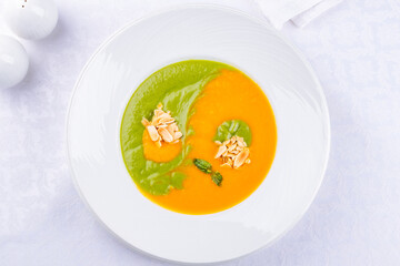Soup cream of pumpkin with spinach on a white plate top view