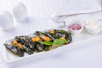 black ravioli with crab and mussels on a white plate