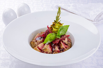 Sliced grilled tuna fillet with vegetables and red sauce on white plate