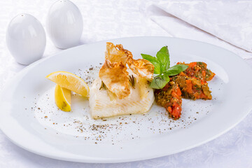 halibut steak on plate with sliced vegetables on a white plate