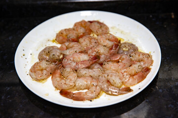 Cleaned and spiced pink shrimp on the plate in closeup and selective focus