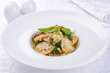 Dumplings with sour cream and herbs and mushrooms on white plate