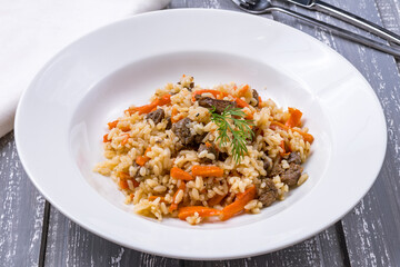 pilaf with beef on white plate on grey table