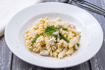 Pasta with chicken and green beans on white plate