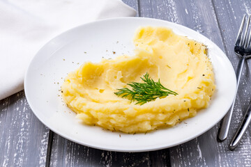 mashed potatoes on a white plate on grey wooden table - 500634342