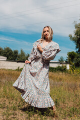 Fototapeta premium A young woman with bare feet in a long country dress dances in a field