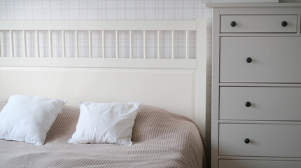 The interior of the room in beige tones with a bed and pillow, closet and flowers on it