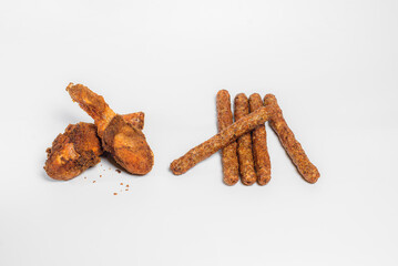 fried chicken drumsticks in oil and breadcrumbs lie on a white background in two pieces with chopsticks