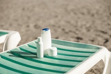 Suntan product bottles on the summer beach. Sunscreen on deck chair outdoors at beach resort